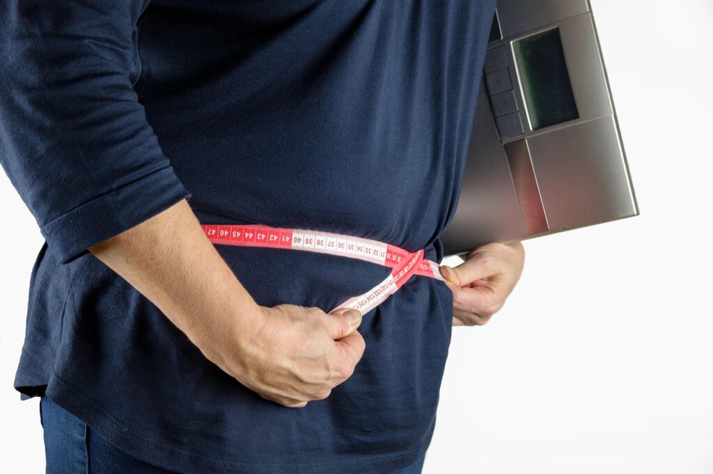 Um homem com fita medindo a circunferencial abdominal.